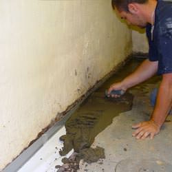 A basement waterproofer installing a perimeter drain system in Elk River