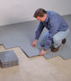 Contractors installing basement subfloor tiles and matting on a concrete basement floor in Eden Prairie, Minnesota