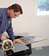 installing a waterproof vapor barrier on a basement floor to prepare for basement carpeting in a Saint Cloud home